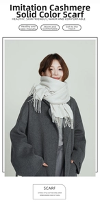 Close-up of soft ivory faux cashmere scarf with elegant tassels on a grey wool coat
