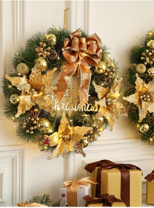 Close-up of lighted Christmas wreath with gold flowers, pine cones and Merry Christmas sign