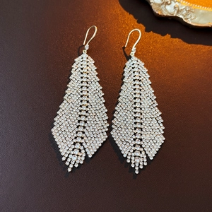 Macro shot of sparkling rhinestone leaf tassel earrings on elegant dark background