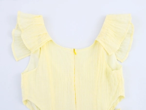 Detail of light yellow textured fabric with ruffle sleeves and invisible zipper closure