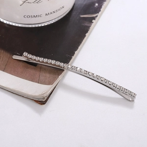 Close-up of silver hair clip with sparkling rhinestones on a white background