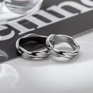 Anelli Mobius minimalisti in argento con trama a onde su sfondo editoriale moderno