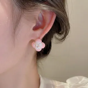 Pink enamel flower stud earrings with zircon stone worn by a model in soft lighting
