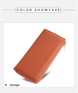 Detail of orange pebble grain leather texture on long zipper wallet with gold hardware