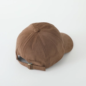 Detail of adjustable metal buckle and cotton twill texture on brown baseball cap