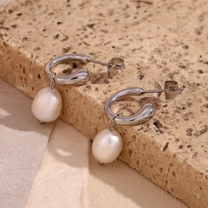 Close-up of silver C-hoop earrings with natural white freshwater pearl on stone base