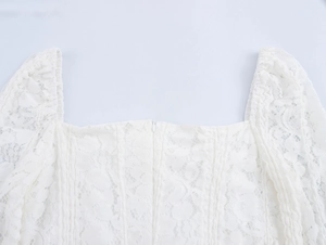 Detailed view of white floral lace fabric with square neckline and back zipper closure