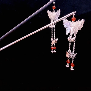 Detail of silver butterfly hairpin with red bead tassels and intricate hollow metalwork