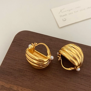 Close-up of vintage gold multi-layer ribbed earrings with delicate pearl accents