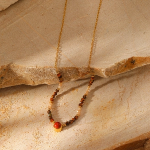 Macro shot of bohemian natural stone beads and gold plated chain on a textured rock surface