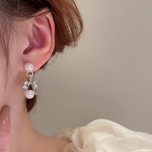 Macro view of elegant double pearl earrings with sparkling crystal accents on a model