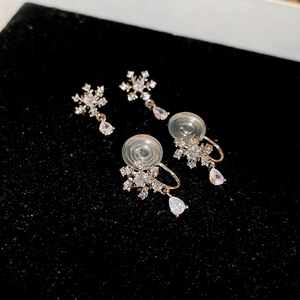 Macro detail of snowflake zircon clip earrings with a teardrop pendant and soft padding