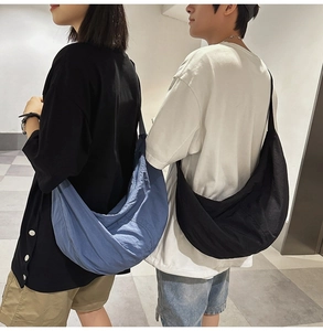 Grands sacs croissants en nylon bleu et noir portés par un couple au style urbain