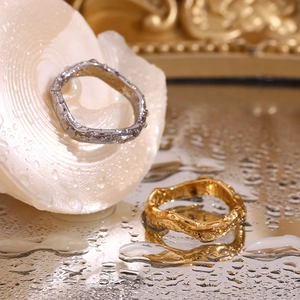 Macro shot of gold and silver hammered wavy rings reflecting on wet surface