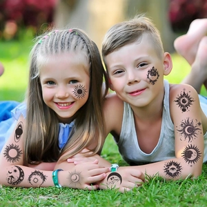 Close-up of black sun and moon temporary tattoos on children's arms and cheeks