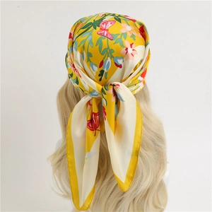 Gele zijden sjaal met bloemen en vlinders geknoopt op een mannequin met haar