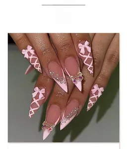 Detail of almond press-on nails featuring 3D pink bows, pearls and ribbon art design