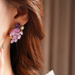 Detail of vintage leaf earring with purple gemstone and pearl on golden metal