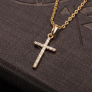 Collar de cruz dorada para mujer con circonitas brillantes sobre un fondo oscuro fino