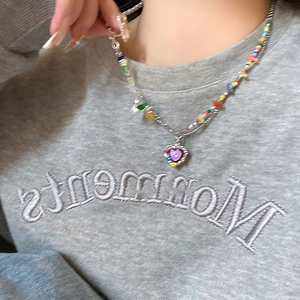 Close-up of a colorful beaded necklace with a purple heart pendant on a person