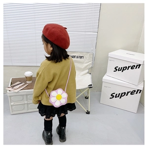 Toddler wearing a cute purple flower-shaped crossbody bag in a modern home setting