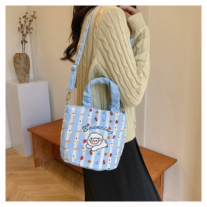 Light blue striped canvas bucket bag with cute cartoon sheep and adjustable strap on a model