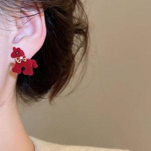 Close-up of red flocked pony earring with gold bow and pearl detail on ear