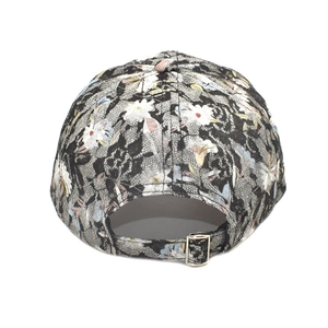 Détail de la casquette en dentelle florale montrant la boucle réglable en métal argenté