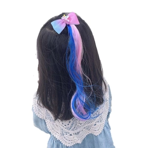 Girl wearing a unicorn bow hair clip with long colorful gradient synthetic hair extensions