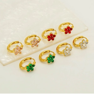 Detailed view of gold flower earrings with colorful zircon stones on marble tray