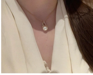 Close-up of elegant 18K gold-plated necklace with a white round pearl and sparkling crystals
