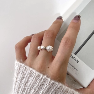 Detalle de anillo ajustable de plata con tres perlas sobre un suéter de punto