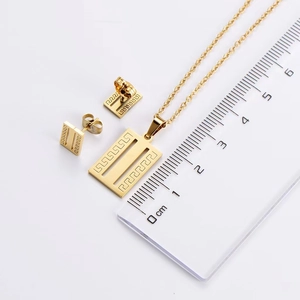 Detailed macro view of gold-plated necklace and earrings set featuring Greek key patterns