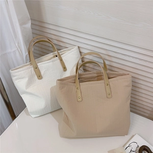 Close-up of cotton tote bags with vertical stripe texture and leather handles