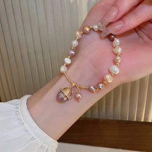 Detail of freshwater pearl bracelet with a lucky cat charm and zircons on a model's wrist