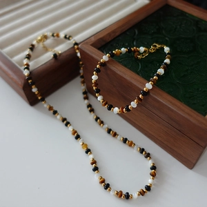 Tiger eye stone beaded necklace and bracelet set with golden accents on wooden boxes