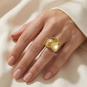 Detail of yellow square-cut crystal ring with silver metal band on satin fabric