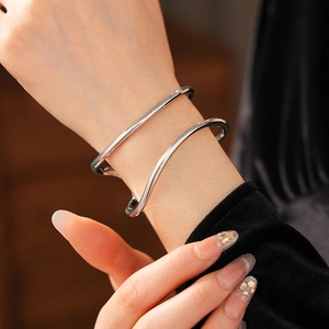Détail des bracelets argentés doubles ondoyants avec une finition métal polie