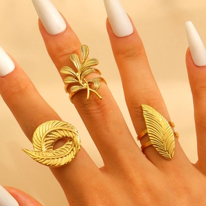 Close-up of gold stainless steel flower and leaf rings set with textured metal details