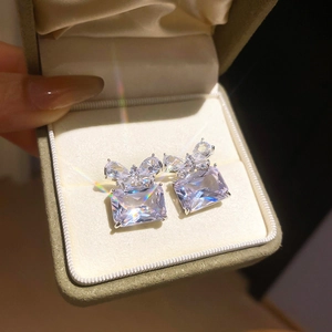 Macro shot of rectangular zircon stud earrings with crystal butterfly knot decoration