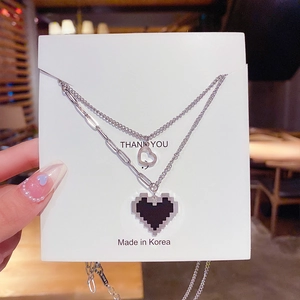 Détail de colliers argentés double couche avec pendentifs cœur sur carte de support