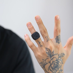 Close-up of black retro gothic stainless steel ring with relief pattern on male hand