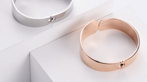 Detail view of mirror-polished silver and rose gold bangles with spring hinge closure