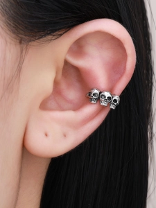 Close-up of triple skull ear cuff in vintage silver finish on a model's ear