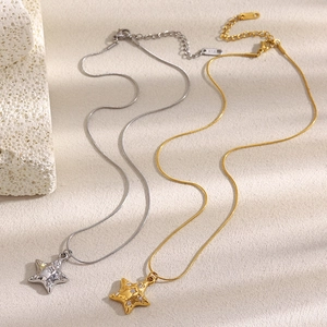 Close-up of gold and silver star necklaces with sparkling crystals on textured stone