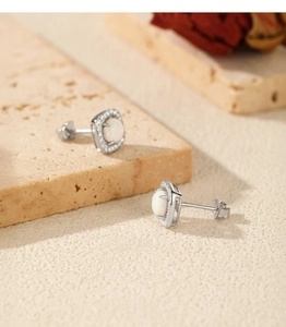Detail of square silver earrings with white opal center and zircon halo on stone