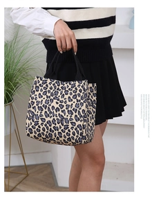 Detailed view of stylish leopard print tote bag with black handles in home setting