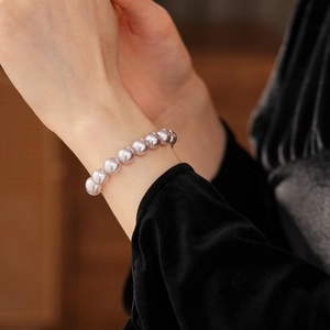 Close-up of elegant lavender pearl bracelet worn by model against black velvet clothing
