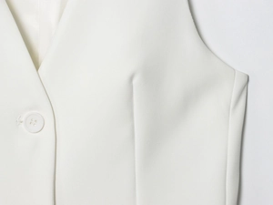 Détail d'un gilet blanc avec fermeture à bouton unique et tissu tissé texturé