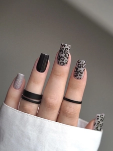 Close-up of square oval press-on nails featuring black gloss and silver glitter leopard print